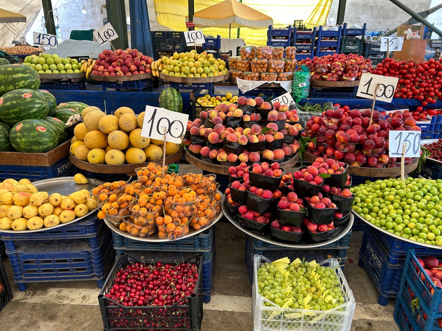 Colorful assortment of fresh fruits at an open market stall, showcasing seasonal produce outdoors.